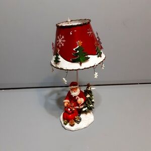 This 5'' x 9.5'' Christmas tealight holder features Santa putting gifts under th